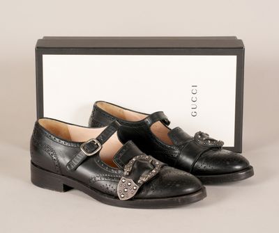 une paire de chaussures en cuir noir à boucles et une boîte