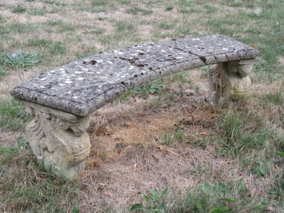 un banc en pierre au milieu d'un champ herbeux