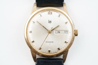 une montre-bracelet en or avec un cadran blanc sur un bracelet noir