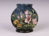 un vase avec des fleurs peintes dessus, posé sur une table