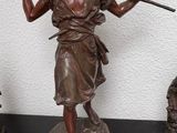 une statue représentant une femme tenant un bâton, posée sur une table