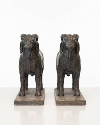 two statues of sheep standing next to each other on a white surface