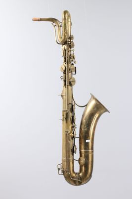 an old saxophone hanging from a string on a white wall