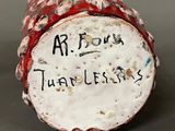a close up of a red and white vase with writing on it