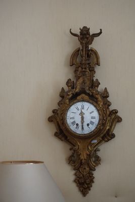 une horloge accrochée au mur à côté d'une lampe