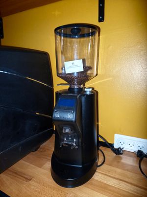 un moulin à café noir posé sur un plan de travail, à côté d'un ordinateur portable