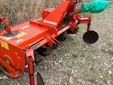 a red tractor plow sitting on the side of the road