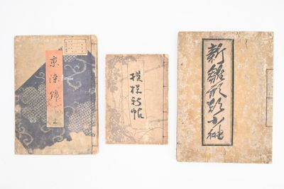 trois vieux livres portant des inscriptions en caractères asiatiques, posés les uns à côté des autres