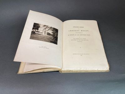 un livre ouvert posé sur une table, à côté d'une photo en noir et blanc