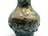 a bronze vase that is sitting on a white surface