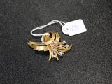 a gold brooch on a black surface with a price tag