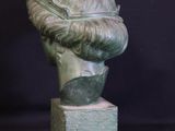 sculpture of a man ' s head on a pedestal with a black background