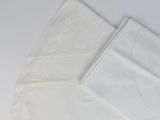 two white napkins on a white table with a pair of scissors