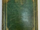 an old book with a green cover and gold trim