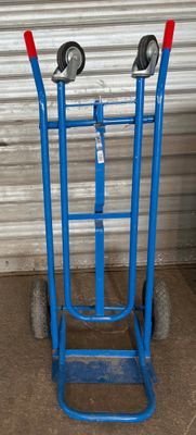 un diable bleu à deux roues devant une porte de garage