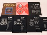 six livres posés sur une table blanche, avec un appareil photo posé dessus