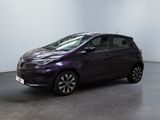 La voiture violette est garée dans une grande pièce au sol noir.