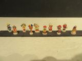 une rangée de figurines miniatures représentant différents personnages, disposées sur une étagère
