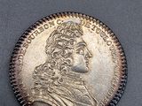 une pièce d'argent à l'effigie d'un homme coiffé d'une couronne
