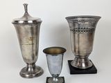 deux vases en argent et une coupe en argent posés sur un fond blanc