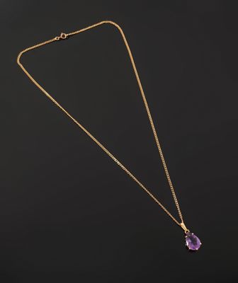 un collier en or orné d'une pierre d'améthorate sur fond noir