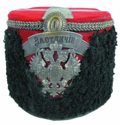 un chapeau rouge et noir orné d'un emblème argenté