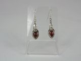 a pair of silver earrings with red stones on them