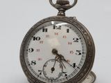 a silver pocket watch sitting on a white surface