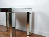 an image of a glass and chrome console table on a hard wood floor
