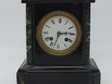 une petite horloge noire avec des chiffres romains