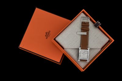 une boîte orange contenant une montre, posée sur une surface noire