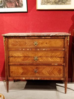 a wooden chest of drawers with a marble top on display