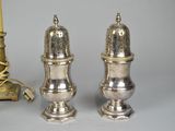 two silver salt and pepper shakers sitting next to a candelier