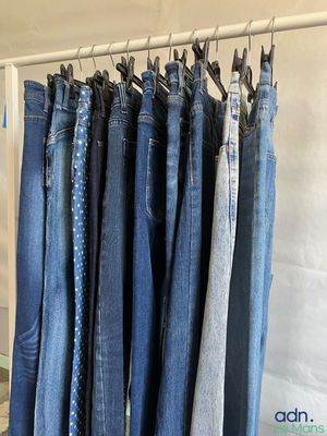 several pairs of blue jeans hanging on a rack in a room