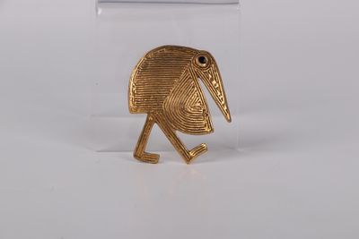 a close up of a gold plated bird on a white surface