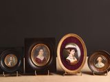 quatre portraits miniatures de femmes sont disposés en rangée sur une table