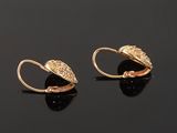 a pair of gold earrings on a black surface
