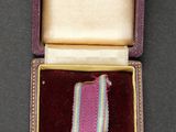 purple ribbon in a case with a gold medal on it