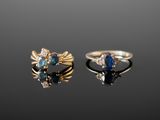 two gold rings with blue stones and diamonds on a black surface