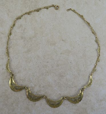 un gros plan d'un collier en or posé sur une surface en marbre