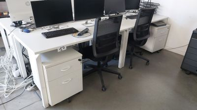 trois ordinateurs posés sur les bureaux de ce bureau