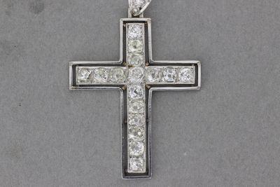 un gros plan d'une croix en argent sertie de diamants sur une surface grise