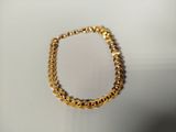 a close up of a gold chain bracelet on a white surface