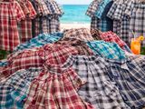 plusieurs t-shirts posés sur une table, avec une plage en arrière-plan