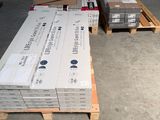 Plusieurs piles de cartons sont empilées sur des palettes dans un entrepôt