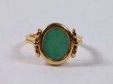 a close up of a gold ring with a green stone