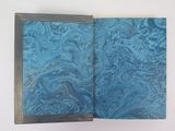 an open book with a blue cover sitting on top of a white table