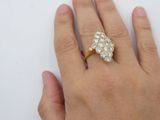a woman ' s hand holding a diamond ring on a white surface