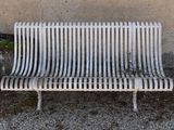 a white metal bench sitting in front of a wall