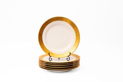 une pile d'assiettes à bord doré posées sur un fond blanc